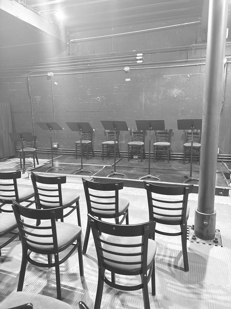 Empty chairs and music stands set for a reading before the audience arrives